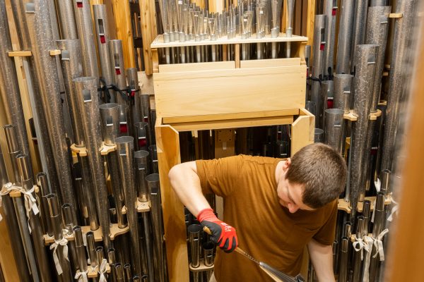 An organ builder working among ranks of pipes inside the Bicentennial Pipe Organ