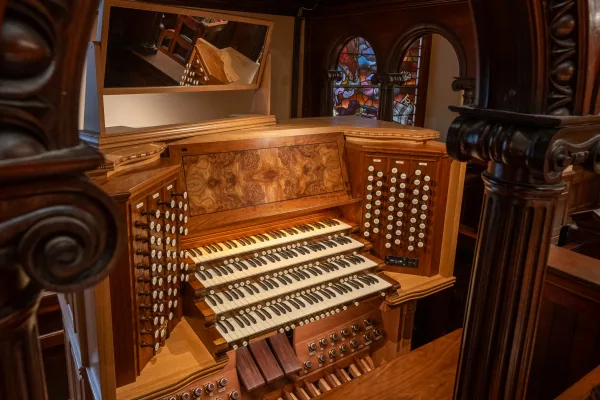 The four-manual console of the Bicentennial Pipe Organ, with stop knobs, keyboards and pedalboard, framed by carved timber