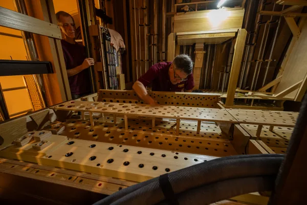 Two organ builders assembling a windchest within the frame of the Bicentennial Pipe Organ