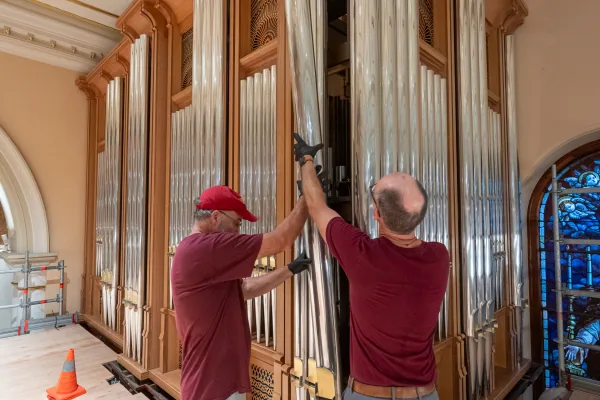 Two Dobson organ builders fitting polished façade pipes to the Bicentennial Pipe Organ