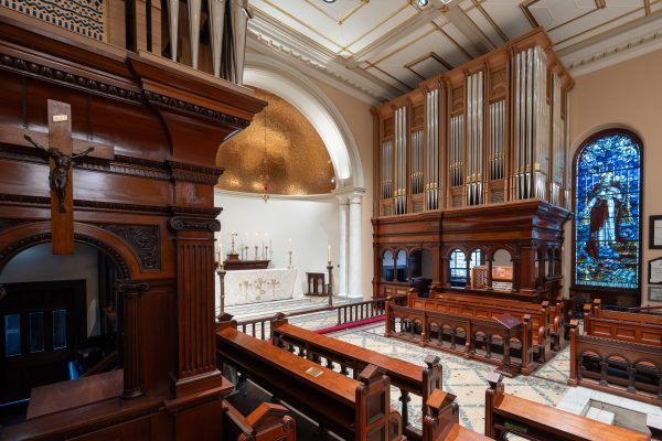The Bicentennial Pipe Organ's pipework and timber case beside a stained glass window in St James' Church