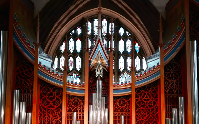 Illuminated pipe organ and stained glass window in a cathedral interior