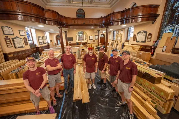 The Dobson Organ Builders team standing among crated organ components in the nave of St James' Church